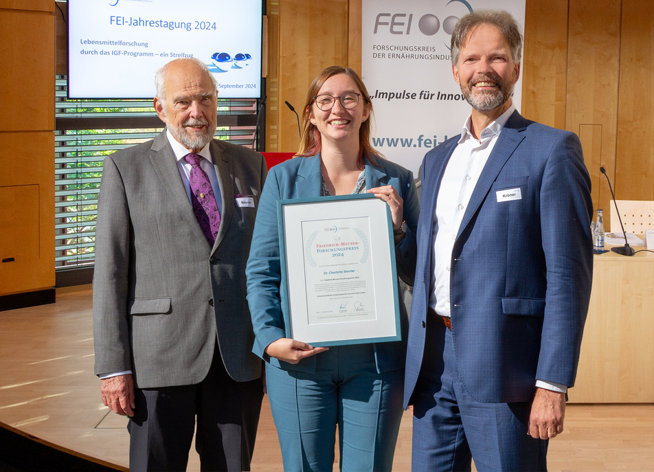 Ausgezeichnet für ihre herausragende Dissertation zum Thema Backlipasen: Dr. Charlotte Stemler mit der Urkunde, die ihm zuvor der FEI-Vorsitzende Dr. Götz Kröner (rechts) überreicht hat; erster Gratulant ist der Namensgeber des Preises, Prof. Dr. Dr. Friedrich Meuser (links).